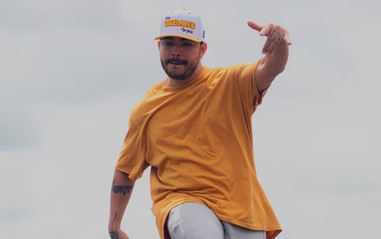 Homem dançando ao ar livre em ponte, vestindo camiseta amarela e boné Usualdance